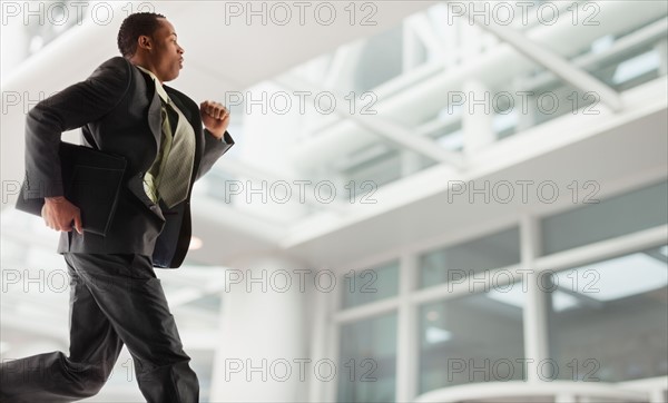 USA, Utah, Salt Lake City, Young businessman running in office building. Photo : Mike Kemp