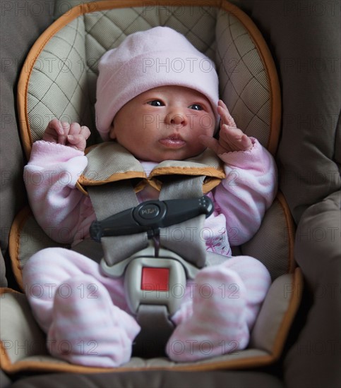 Portrait of newborn girl (0-1months) in car seat. Photo : Mike Kemp