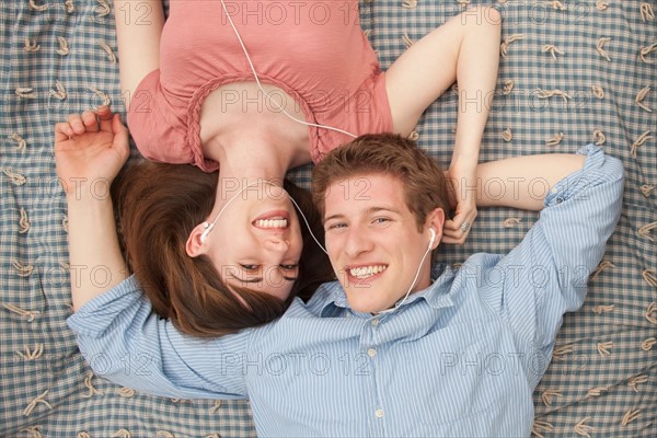 Young couple with mp3 player lying on blanket. Photo : Mike Kemp