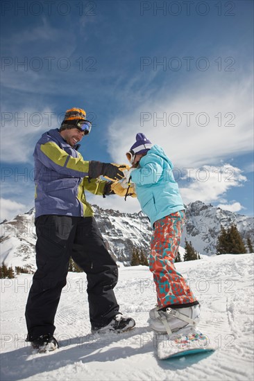 USA, Colorado, Telluride, Father helping daughter (10-11) with snowboard binding. Photo : db2stock