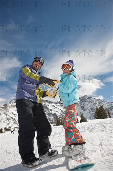 USA, Colorado, Telluride, Father helping daughter (10-11) with snowboard binding. Photo : db2stock