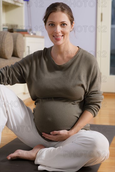 Portrait of expectant mother sitting on exercise mat. Photo : Rob Lewine