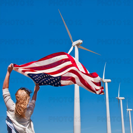 USA, California, Palm Springs, Woman weaving American flag with wind turbines in background. Photo : Daniel Grill