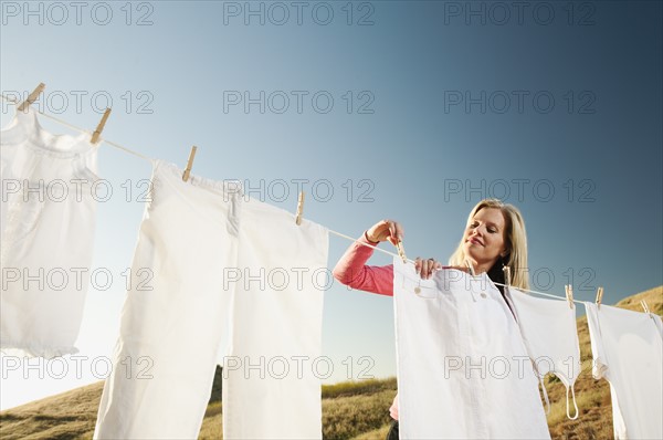 Woman hanging laundry on clothesline .