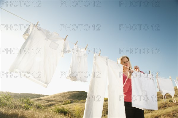 Woman hanging laundry on clothesline .