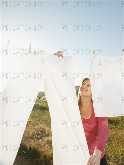 Woman hanging laundry on clothesline .