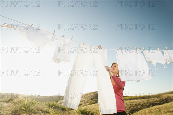 Woman hanging laundry on clothesline .