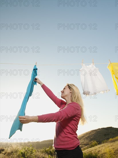 Woman hanging laundry on clothesline .