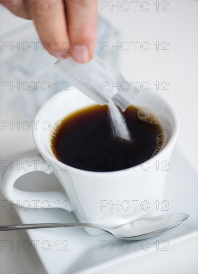Man pouring sweetener into coffee.