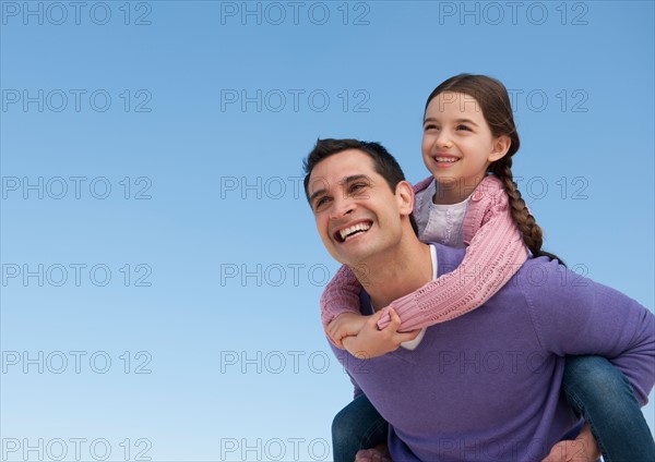 Father giving piggyback ride to daughter (8-9).