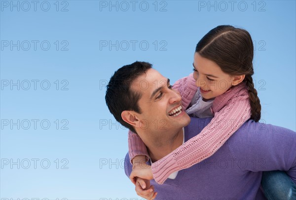 Father giving piggyback ride to daughter (8-9).