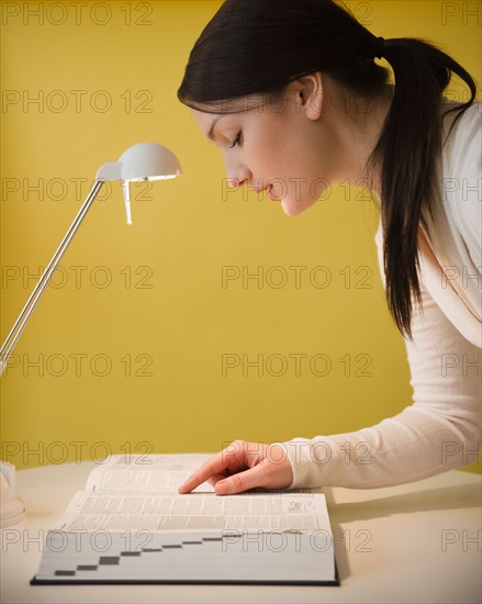 Young woman looking at dictionary. Photo : Jamie Grill Photography