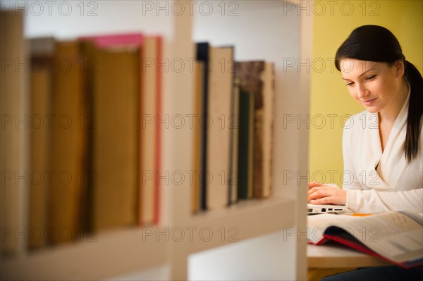 Young woman studying in library. Photo : Jamie Grill Photography