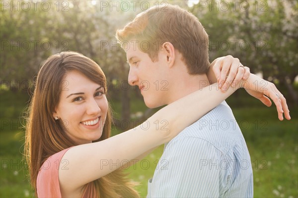 Young couple embracing in orchard. Photo : Mike Kemp