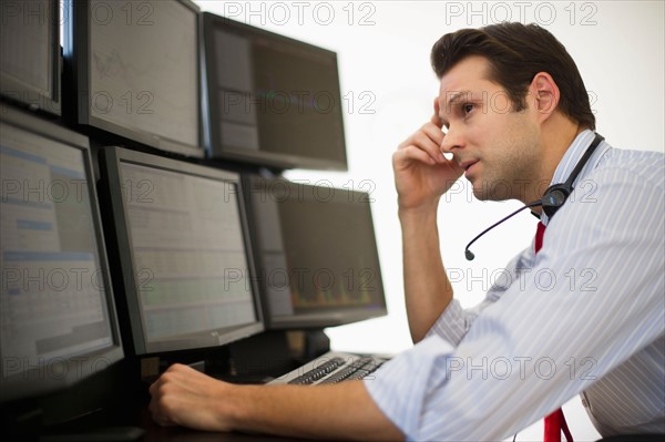 Financial worker analyzing data displayed on computer screen.