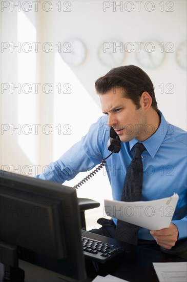 Businessman working on computer and talking on the phone.