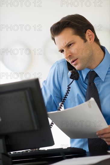 Businessman working on computer and talking on the phone.