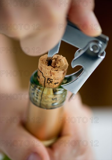 Close-up of man's hands opening wine bottle.