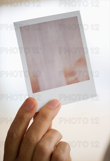 Studio shot of man's hand holding Polaroid photograph.