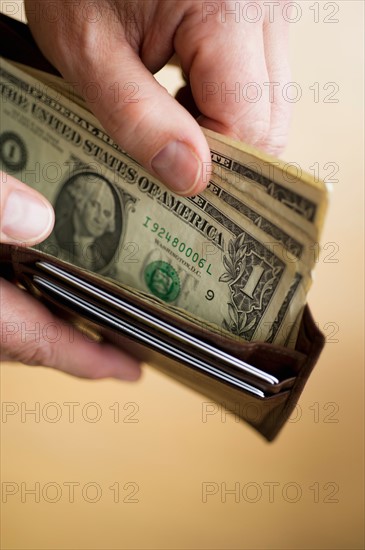 Close-up of man's hands holding wallet with dollar banknotes.
