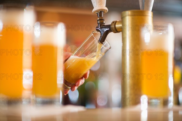 Barman poring beer from beer tap .