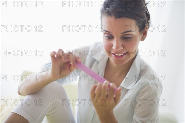 Attractive young woman filing nails.