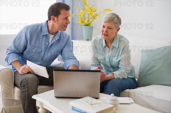 Senior mother and adult son using laptop.