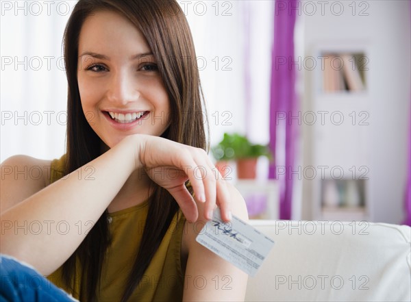 Portrait of smiling young woman holding credit card. Photo : Jamie Grill Photography