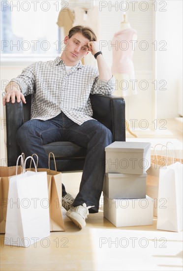 Pensive man sitting in clothes store. Photo : Daniel Grill