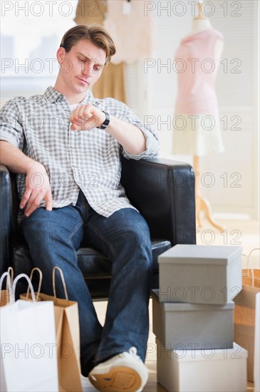 Pensive man sitting in clothes store. Photo : Daniel Grill