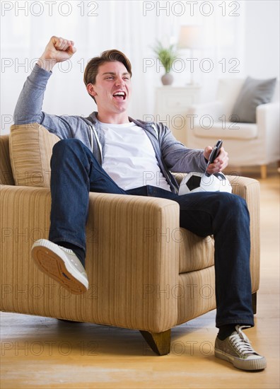 Man sitting in chair and watching TV soccer game. Photo : Daniel Grill