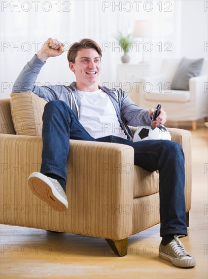 Man sitting in chair and watching TV soccer game. Photo : Daniel Grill