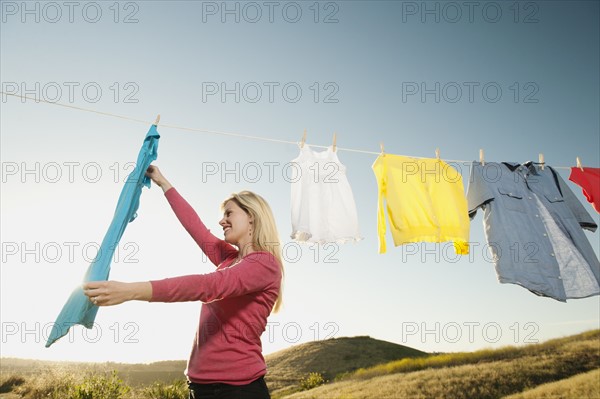 Woman hanging laundry on clothesline .