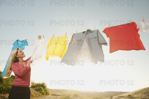 Woman hanging laundry on clothesline .