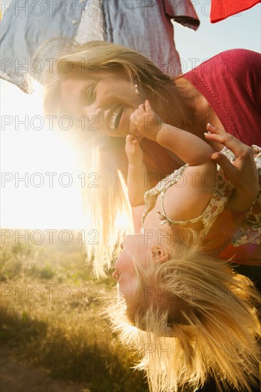 Mother playing with daughter (12-17 months) with laundry on clothesline in background.