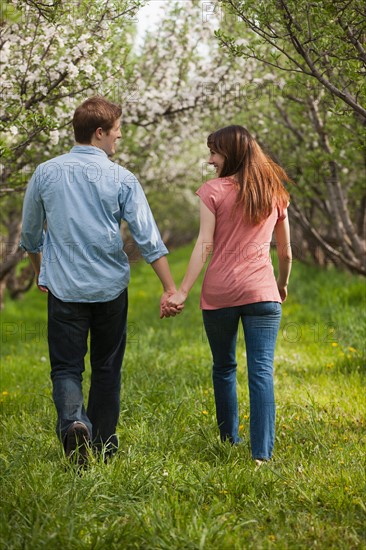 USA, Utah, Provo, Young couple walking through orchard. Photo : Mike Kemp