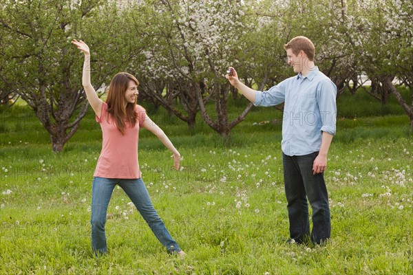 USA, Utah, Provo, Young man photographing young woman in orchard. Photo : Mike Kemp