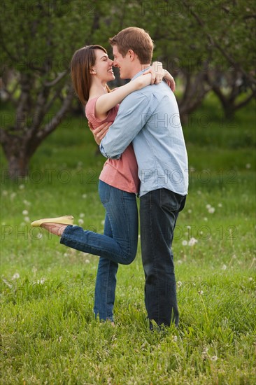Young couple embracing in orchard. Photo : Mike Kemp