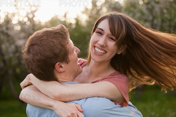 Young couple embracing in orchard. Photo : Mike Kemp