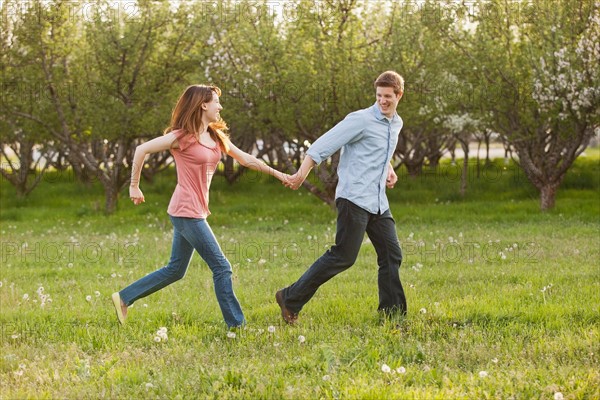 USA, Utah, Provo, Young couple running through orchard. Photo : Mike Kemp
