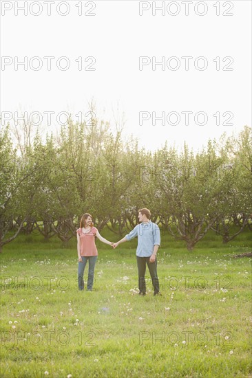 USA, Utah, Provo, Young couple walking through orchard. Photo : Mike Kemp