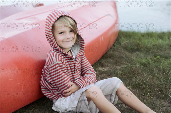 Portrait of boy (4-5) sitting by canoe. Photo : King Lawrence