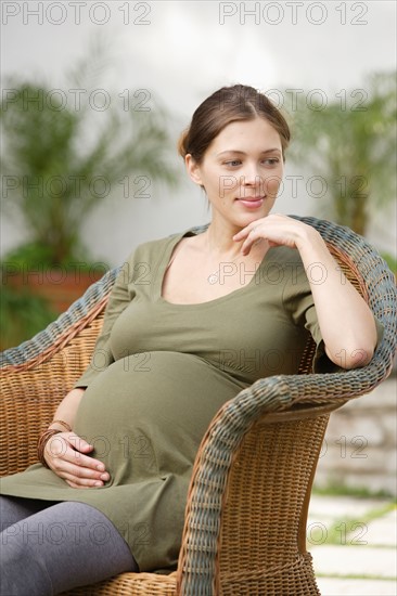 Pregnant woman sitting in wicker chair, daydreaming . Photo : Rob Lewine