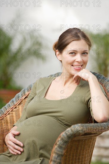 Portrait of pregnant woman sitting in wicker chair. Photo : Rob Lewine