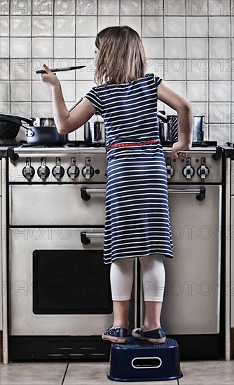 Girl (8-9) cooking in kitchen . Photo : Justin Paget