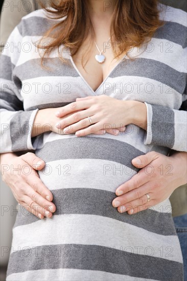 Man's hands on pregnant woman's belly. Photo : Rob Lewine