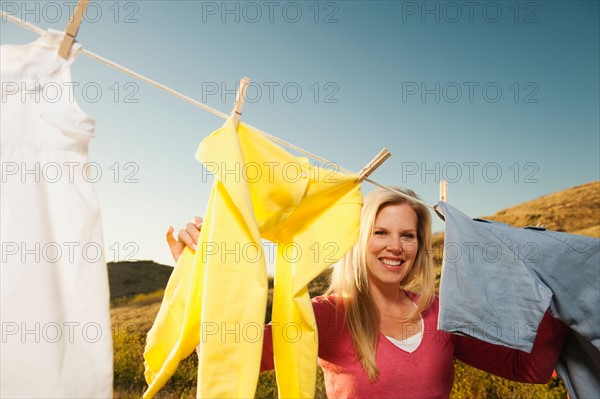 Woman hanging laundry on clothesline .
