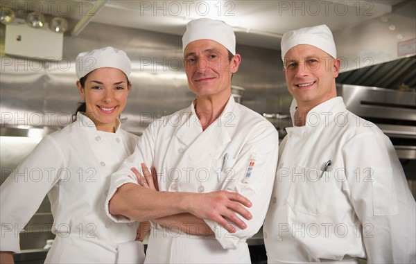 Three chefs posing in kitchen.