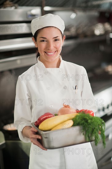 Smiling chef holding fresh vegetables.