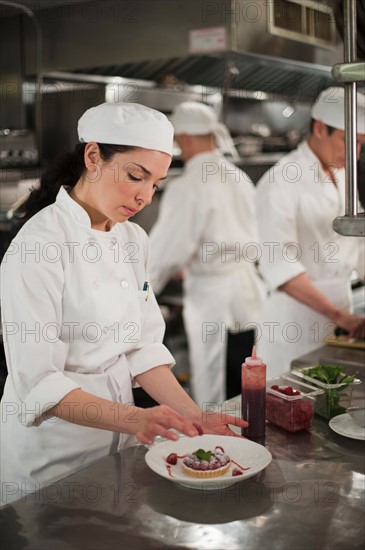 Chefs preparing food in kitchen.